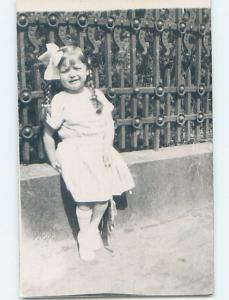 old rppc ANTIQUE WROUGHT IRON FENCE BEHIND GIRL WITH PIGTAILS HM1117