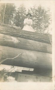 Postcard RPPC Photo Woman on large logs logging lumber 22-13994