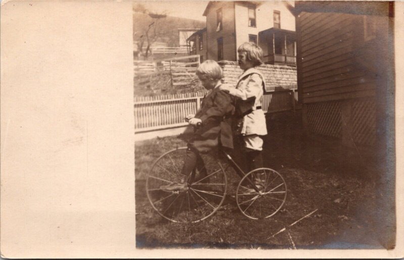 Real Photo Postcard Two Children on Tricycle in Yard of a House