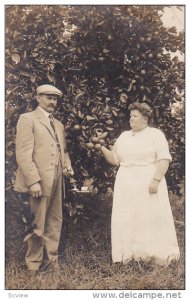 RP; Man and woman standing by an apple tree, 1904-1920s