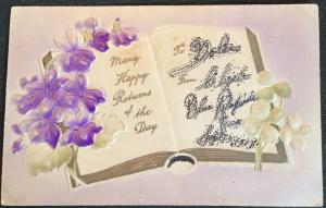 Postcard Unused w/writing on back “Many Happy Returns” embossed Flowers LB