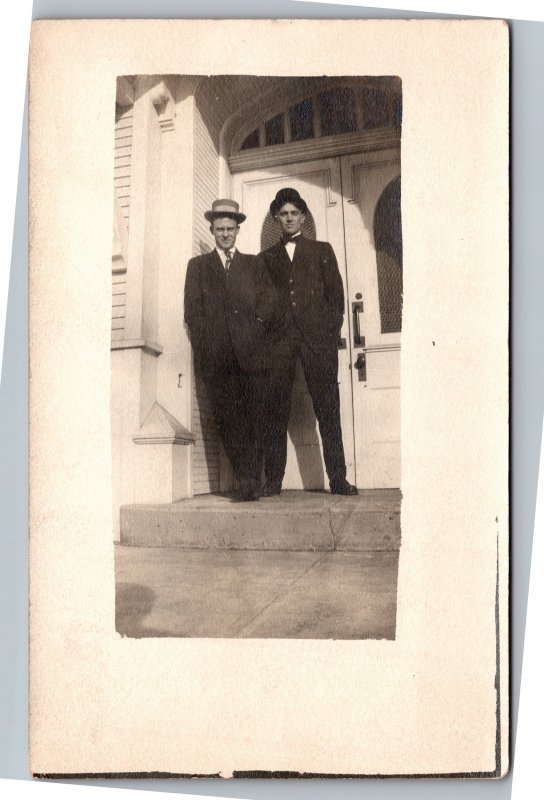 RPPC Two men standing outside double door building in suit and hat