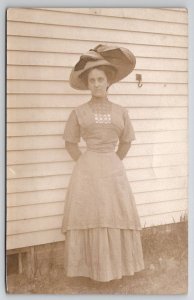 RPPC Lovely Lady Large Hat Pretty Dress Standing Alongside House Postcard O27