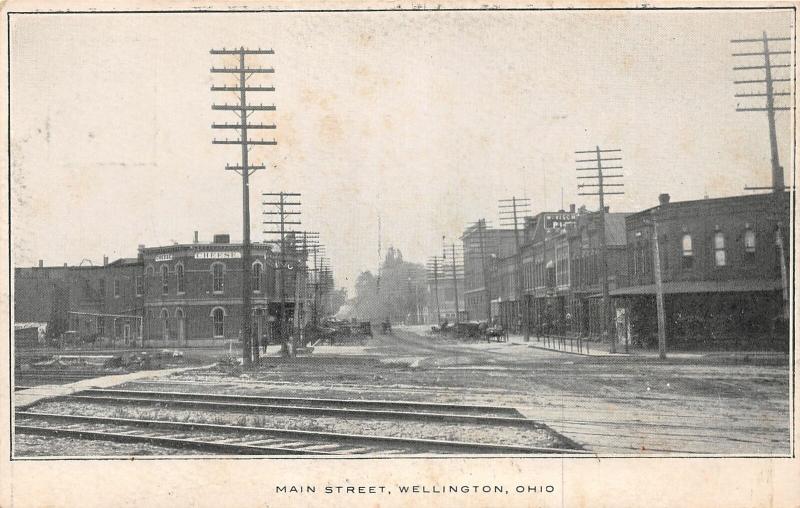 F64/ Wellington Ohio Postcard c1910 Main Street Stores Railroad