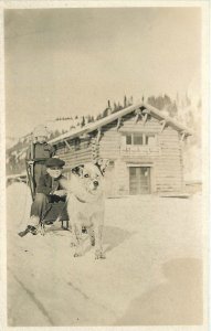 Postcard RPPC C-1910 Children sled snow dog log cabin 23-11039