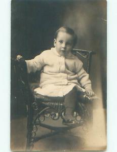 Pre-1918 rppc CHILD IN SWEATER SITS ON RATTAN CHAIR o2024