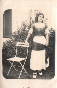 VINTAGE POSTCARD c. 1910-1918 PRETTY WOMAN STANDING BESIDE CHAIR WITH DRESS WRAP