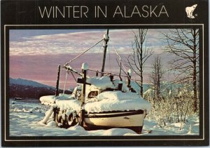 postcard Alaska Scene - heavy snow covering old boat under midnight sun