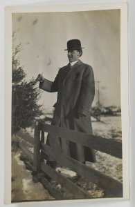 RPPC Man in Snow w/ Derby Hat, Long Coat Side Profile Pose At Fence Postcard R4