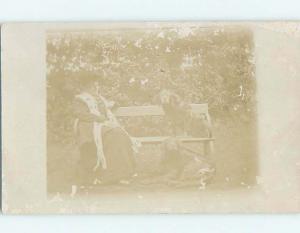 Faded c1910 rppc ONE DOG ON BENCH WITH WOMAN AND ANOTHER DOG ON GROUND HM0493