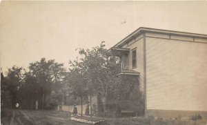 c1910 RPPC Real Photo Postcard Woman In Front Of Large House Sidewalk Dirt Road