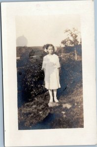 postcard rppc Girl in white with bows in hair standing outside 1918-1930 AZO