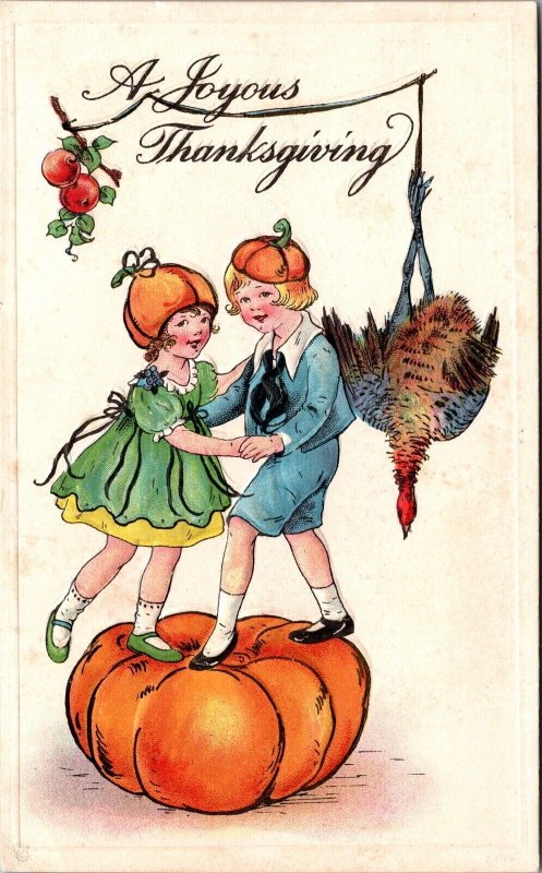 Thanksgiving Postcard Boy and Girl Wearing Pumpkin Hats Dancing on a Pumpkin