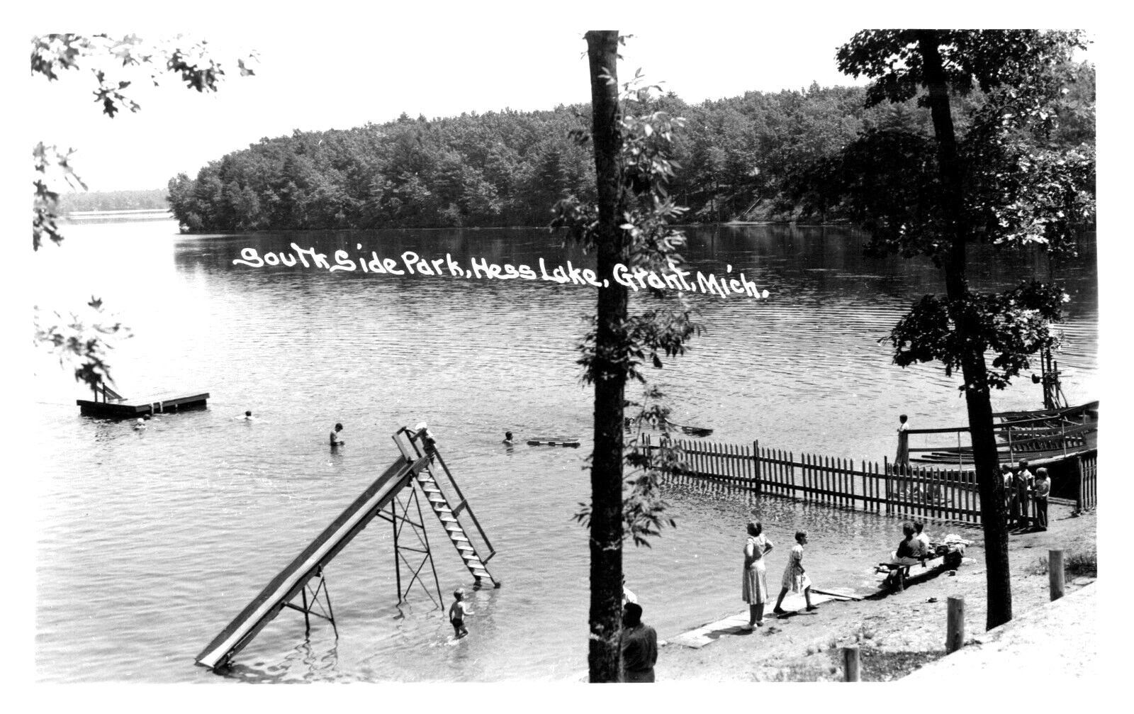A photo of a large municipal pool with a water slide and diving board