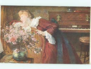 c1910 Postcard LITTLE FLOWERING TREE IN FLOWERPOT BESIDE WOMAN AND PIANO AC3642