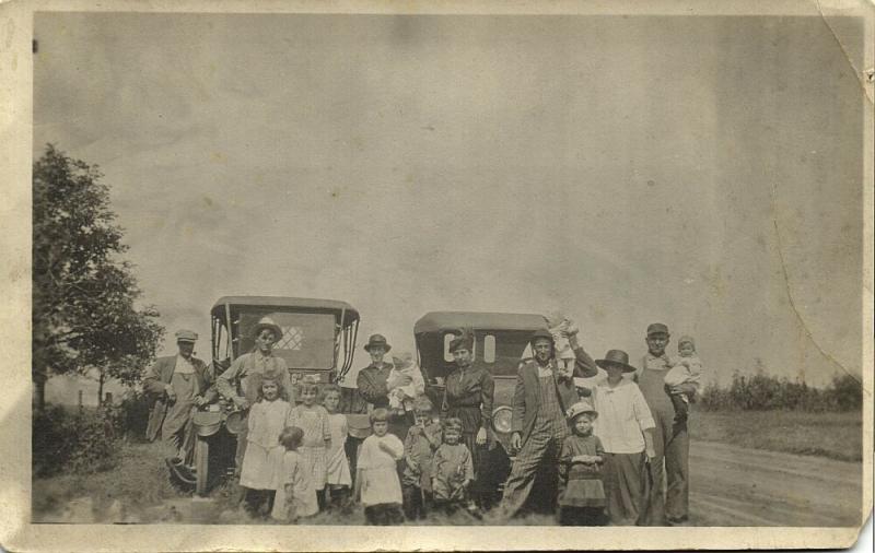 Two Proud Families in Front of their Old Cars of Unknown Brand (1920s) RPPC