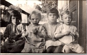 Real Photo Postcard Four Children Sitting on a Porch Together
