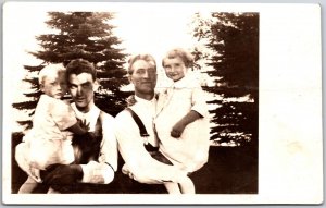 Two Men Carrying Children Half Body Photograph Pines in Background RPPC Postcard