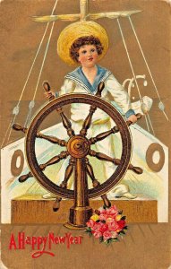YOUNG BOY OR GIRL IN SAILOR SUIT~SHIP WHEEL STEERING BOAT-GILT NEW YEAR POSTCARD