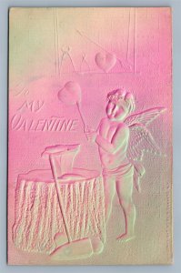 VALENTINE ANTIQUE DEEPLY EMBOSSED POSTCARD CUPID HAMMERING THE HEART