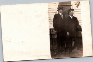 RPPC Two men in suits hanging outside of house brothers maybe