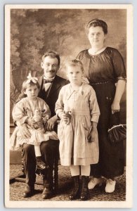 RPPC Smiling Parents Raise Bright Girls~Little Dolls in Hand~BOWTIE~Wire Glasses