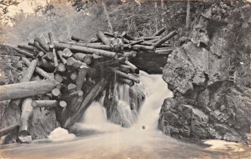 MAN SITTING ON DAM OF LARGE LOGS~SMALL WATERFALL~REAL PHOTO POSTCARD1910s