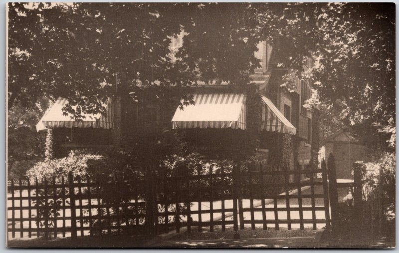 Two-Story House with Striped Window Awnings Behind Large Trees, Vintage Postcard