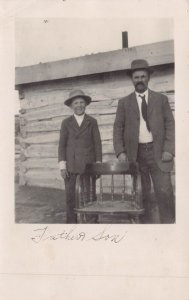 FATHER & SON IN FRONT OF PLANK LOG BUILDING-1910 REAL PHOTO POSTCARD