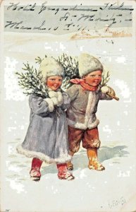 YOUNG BOY & GIRL CARRY SMALL TREES THROUGH SNOW-ARTIST FEIERTAG 1911 POSTCARD