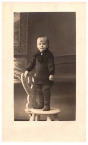 Boy in  winter clothes standing on chair