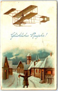 Man Standing in the Snow Covered Street Looking at Airplane  - Vintage Postcard