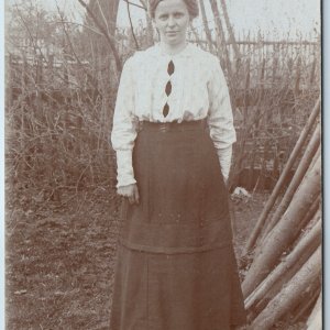 c1910s Cute Woman Outdoors RPPC Fence Winter Dress Fashion Fall Stick Photo A212