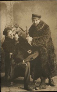 Men in Studio Fur Coats Liquor Bottle c1910 Real Photo Postcard