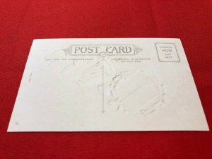 embossed postcard SANTA sitting on earth with hammer to nail a wreath on world