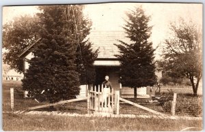 Old Woman Standing Outside Her Home, Wearing Dress with Apron - Vintage Postcard