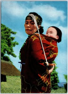 VINTAGE CONTINENTAL SIZE POSTCARD AN AINU WOMAN TENDING TO HER BABY (JAPAN)