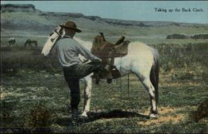 Cowboy Mounting Horse - Taking Up the Back Cinch c1910 Postcard