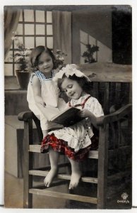 Two little girls reading. Postcard.