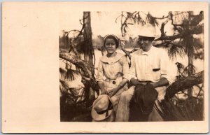 Man and Lady Resting On Trunk Hat Real Photo RPPC Postcard