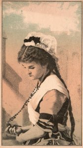 1880s-90s Woman In Dress with Cap Holding Beaded Necklace Cross Trade Card