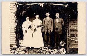 RPPC Double Wedding~Brides & Grooms Under Garland & Bow Arch~Oversize Coat 1910