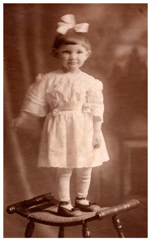 Young Girl standing on Chair ,Bow in hair