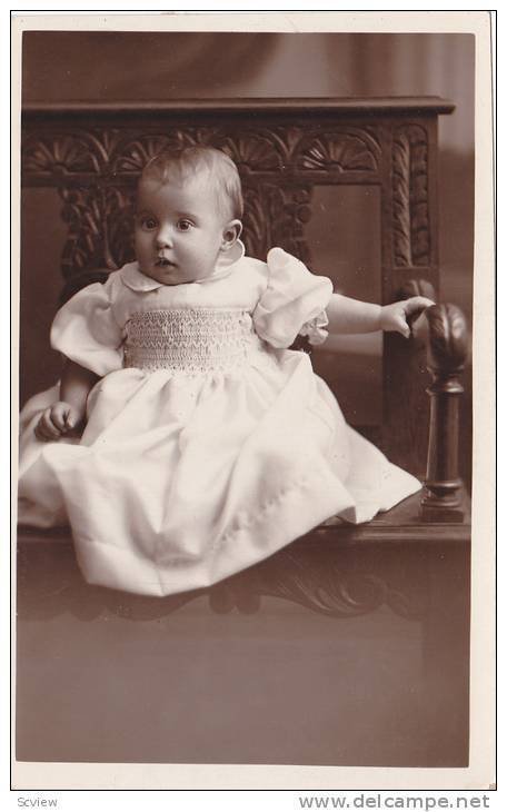 RP; Baby girl wearing white gown, sitting in a chair, 10-20s