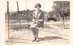 WOMAN SITTING ON SWING~LABELED HOWITT~AUTO IN BACK REAL PHOTO POSTCARD 1926