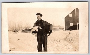 Farmer in Snow with Goose & Black Piglet Under Arms~Dog in Barnyard~1915 RPPC