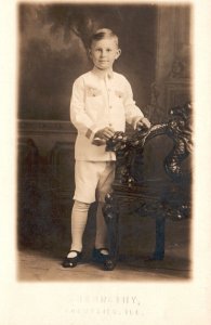 Vintage Postcard Young Boy in White Jacket & Pants by Chair Portrait RPPC