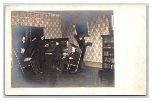 RPPC Men in Parlor Gathered Around Piano Rocking Chairs UNP Postcard S3