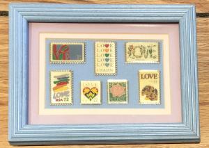 7 Love Stamp Pins Under Glass in a Wood Frame