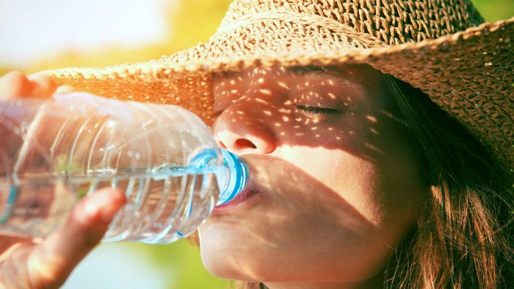 woman with a straw hat drinking water